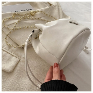 Detailed close-up of white lychee leather bucket bag with gold chain and drawstring