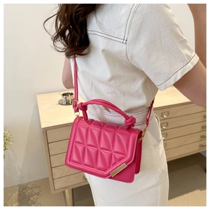 Close-up of rose red quilted crossbody bag with gold metal trim and knotted handle detail