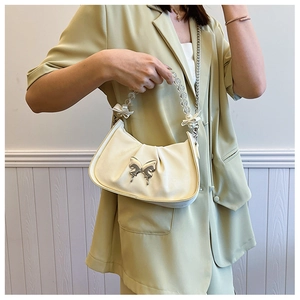 Detail of beige saddle bag with metallic butterfly, pleated texture and beaded chain handle