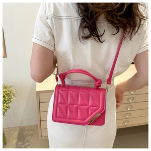 Detail of rose red quilted crossbody bag with gold metal trim and triangle stitching