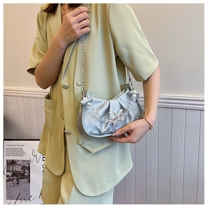 Silver velvet crescent bag with butterfly chain on model wearing a green suit