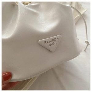 Macro detail of the white drawstring bucket bag with lychee texture and logo plaque
