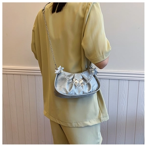 Detail of silver velvet saddle bag featuring bow metal clasp and beaded handle strap