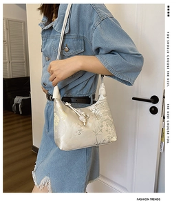 Detail of beige silk hobo bag with traditional Chinese embroidery and beaded tassel