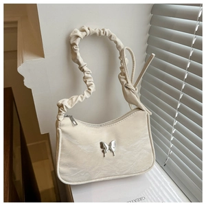 Detail of cream hobo bag featuring a silver butterfly buckle and ruched strap texture