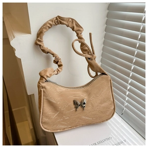Detail of beige pleated shoulder bag featuring a silver butterfly buckle and textured fabric