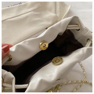 Detail of white drawstring bucket bag showing gold magnetic closure and interior lining