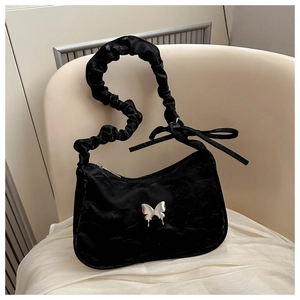 Detail of black velvet shoulder bag featuring silver fluid butterfly and scrunchie strap