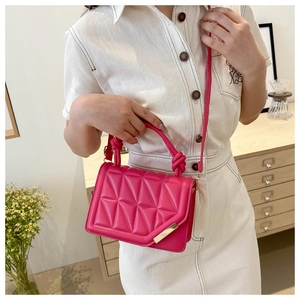 Close-up of vibrant rose pink crossbody bag with knotted handle and gold metal details