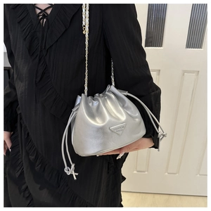 Detail view of silver drawstring bucket bag with gold chain strap on a black dress
