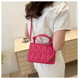 Detail of hot pink quilted handbag with gold hardware and stylish knotted top handle