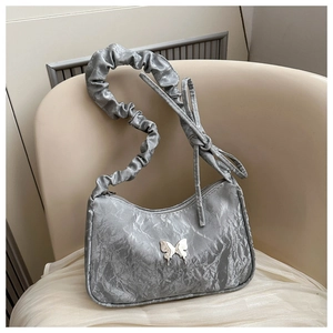 Detail of silver pleated shoulder bag with metal butterfly clasp and ruffles