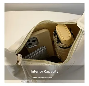 Top-down view of beige shoulder bag interior holding phone, umbrella, and wallet