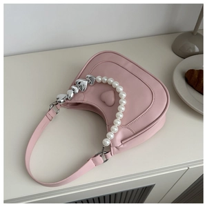 Detailed shot of pink heart-shaped handbag with decorative pearl and metal heart chain