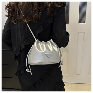 Detailed back view of a silver metallic drawstring bucket bag with a chain strap on a model
