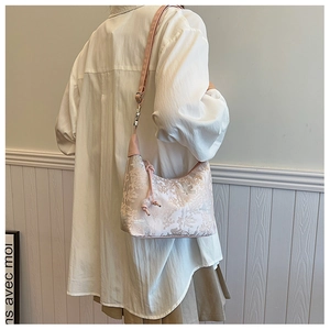 Detail of floral brocade jacquard texture on pink crescent shoulder bag with strap