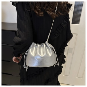 Detailed view of silver drawstring bucket bag with metallic finish and metal chain strap