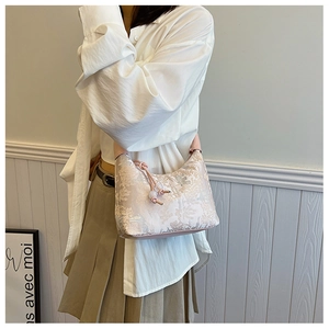 Close-up of floral jacquard fabric and pink leather drawstring knot on the handbag