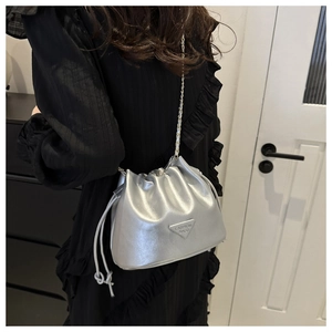Silver bucket bag with chain strap and drawstring detail shown on model in indoor setting