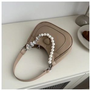 Detail of light brown crescent bag with heart embossing and decorative pearl chain strap