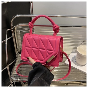 Detail of rose pink quilted crossbody bag with knot handle and golden buckle