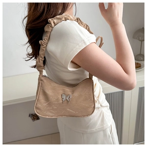 Detail of a chic marble pattern shoulder bag with a ruched strap and silver butterfly accent