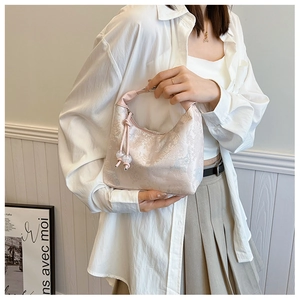 Detail of light pink floral jacquard fabric and drawstring with clear beads on a handbag