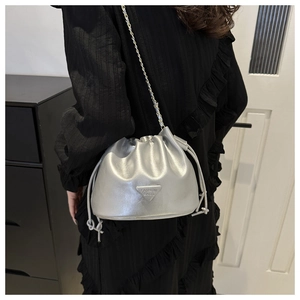 Detail view of silver drawstring bucket bag featuring a metallic triangle fashion plate