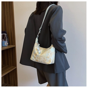 Detail of silk jacquard shoulder bag featuring light blue fabric and gold floral patterns