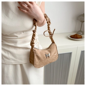 Detail of beige shoulder bag with silver butterfly hardware and ruched handle texture