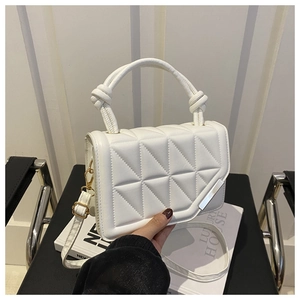 Detail of white quilted crossbody bag with wave-edge flap and knotted top handle