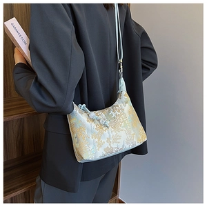 Detail of mint green crescent bag featuring traditional Chinese floral embroidery texture