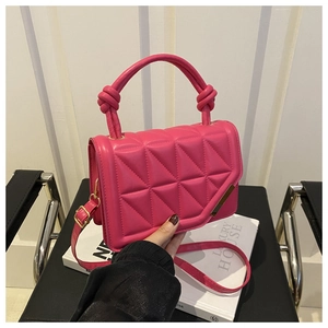 Detail of fuchsia quilted handbag with knotted handle and elegant gold-tone metal hardware