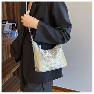 Detail of light blue crescent bag with floral jacquard fabric and beaded zipper on model