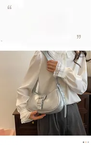 Détail du sac croissant argenté avec fini métallisé et large boucle sur la bandoulière
