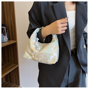Detail of light blue Chinese style handbag with golden embroidery and beaded charms