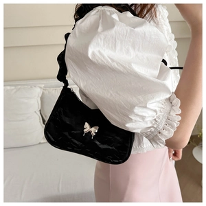 Detail of black pleated shoulder bag with silver butterfly buckle and ruffled strap