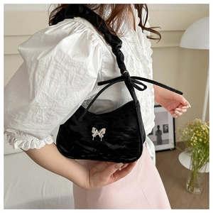 Detail of black pleated shoulder bag with silver butterfly buckle and ribbon strap