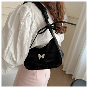 Detail of black velvet hobo bag featuring silver butterfly and ruched bow shoulder strap