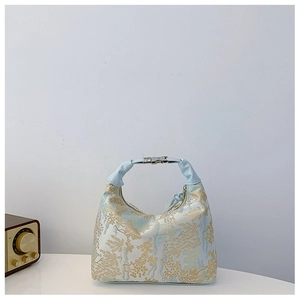 Detail of blue brocade landscape embroidery and silver metal buckle on a retro handbag