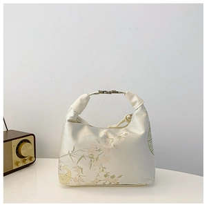 Detailed macro of white satin handbag featuring elegant pink floral embroidery and metal handle