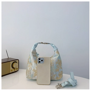 Detail of light blue floral jacquard handbag with metallic hardware and shoulder strap