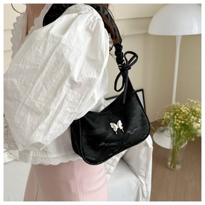 Detail showing black gathered underarm bag with white butterfly and ruffled strap on shoulder