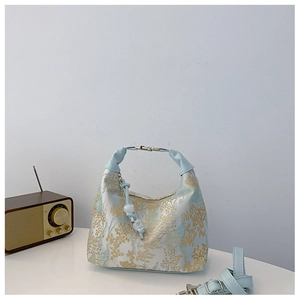 Detail of blue and gold landscape jacquard fabric on a crescent hobo handbag
