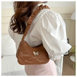 Brown pleated leather shoulder bag with silver butterfly buckle shown on model