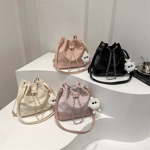 Multi-color leather bucket bags with chain straps and plush charms in white space