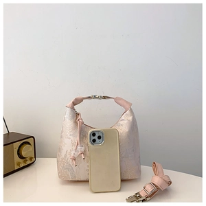 Detail of light pink floral jacquard handbag with phone for size reference and strap