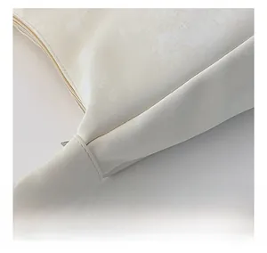 Detailed close-up of cream shoulder bag stitching and silver metal strap ring