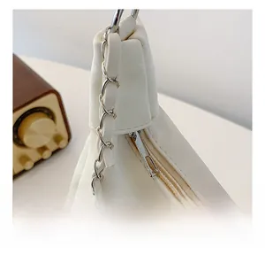 Close-up of smooth zipper closure and silver metal chain strap on white leather bag