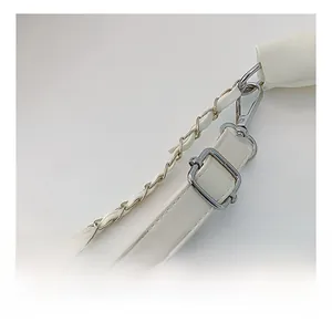 Detail of adjustable white leather shoulder strap and silver metal chain on minimalist bag